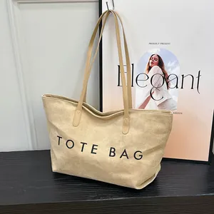 Minimalist beige oversized tote bag with black lettering and long shoulder straps
