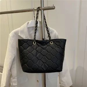 Schwarze gesteppte Shopper Tasche mit Goldkette am Kleiderbügel präsentiert