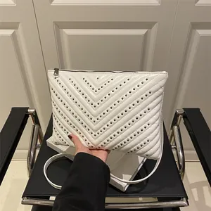 Chic white quilted crossbody bag with metal studs and detachable strap on white box