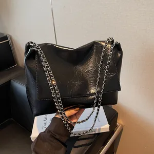 Fashionable black tote bag with glossy wrinkled leather and silver chain strap details