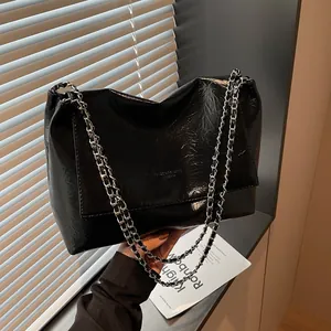 Black crinkled patent leather tote bag with silver chain straps and flap closure