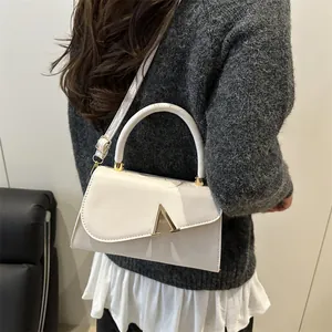 Elegante cremeweiße Leder-Umhängetasche mit goldener V-Schnalle am Modell gezeigt