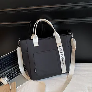 Minimalist black canvas lunch tote bag with white EVES CAMIER lettered handle