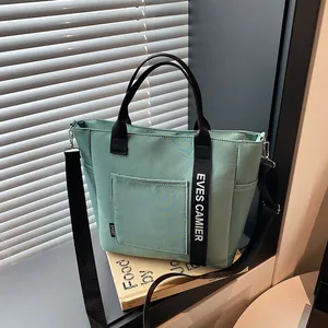 Pale green insulated tote lunch bag with black shoulder strap and top handles for work