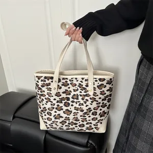 Fashionable leopard print tote bag with beige leather handles and gold stud details