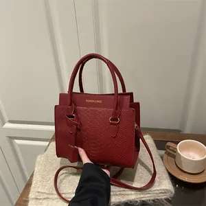 Sac à main bordeaux en cuir gaufré crocodile avec détails dorés et bandoulière