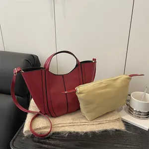 Sac seau en cuir bordeaux avec pochette en toile beige sur une écharpe en laine