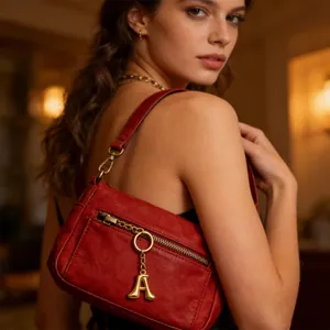 Dettaglio borsa a spalla in pelle rossa vintage con ciondolo a lettera A dorata
