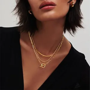 Detailed view of layered gold necklaces with OT buckle and snake chain on model