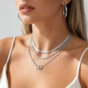 Close-up of layered silver chain set with OT toggle clasp and matching hoop earrings