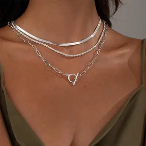 Close-up of layered silver chain set with snake, rope, and paperclip links with OT buckle