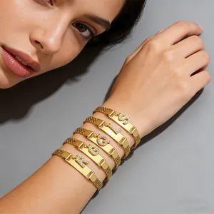 Detail von goldenen Mesh-Kettenarmbändern mit gravierter gebogener Platte und Kristallanhängern