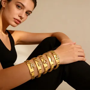 Detailansicht des goldenen Mesh-Armbands mit funkelnden Buchstabenanhängern und Metallplatte