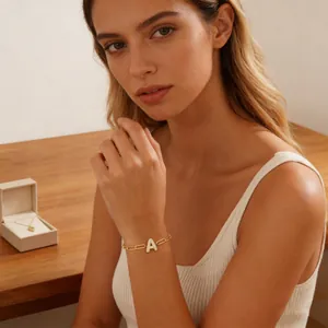 Detailopname van een gouden papercliparmband met een micro-pave letter A hangertje