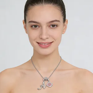 Close-up of zircon clover pendant and cursive letter A charm on a silver necklace