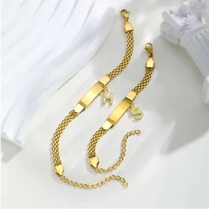 Details goldener Mesh-Armbänder mit polierten Metallplatten und Kristall-Buchstabenanhängern