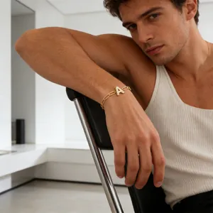Gedetailleerd beeld van een gouden paperclip armband met een met zirkoon bezette letter A