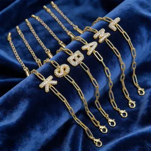 Macro-opname van gouden paperclip armbanden met schitterende zirkonia initialen