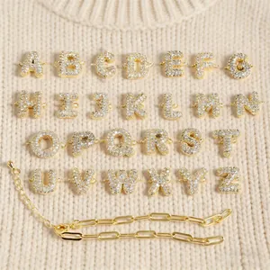 Detail van gouden letterhangers met zirkonia en een stijlvolle paperclip ketting