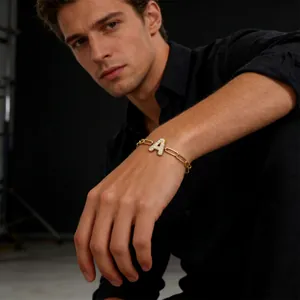 Detail van gouden schakelarmband met grote met zirkonia bezette letter A hanger op model