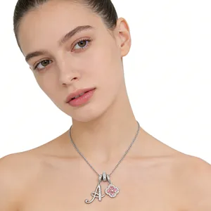 Close-up of a silver clover pendant with pink gem and a crystal-set letter A on a thin chain