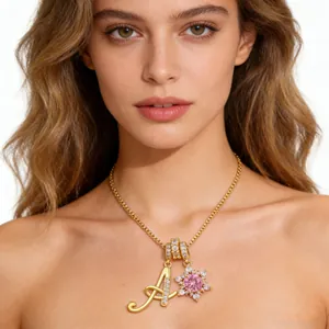 Detail of gold letter A necklace with pink snowflake pendant worn by a model