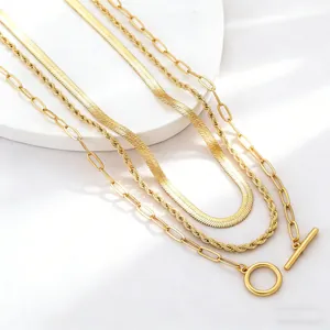 Macro shot of layered gold necklaces with snake, rope chains and vintage toggle clasp