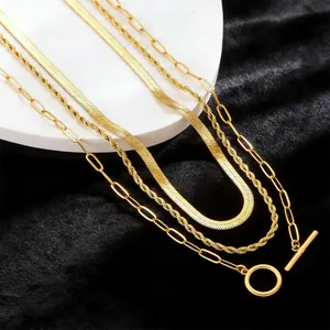Close-up of gold layered paperclip, rope, and herringbone chains with an OT toggle clasp