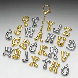 Dettaglio di ciondoli con lettere 3D in oro e argento con chiusura a moschettone per borse