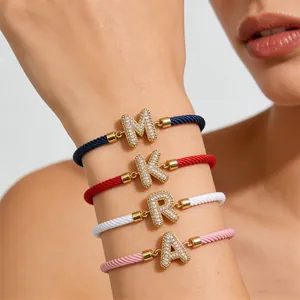 Detailansicht gewebter Armbänder mit Zirkonia-Buchstaben A-Z am Handgelenk des Models