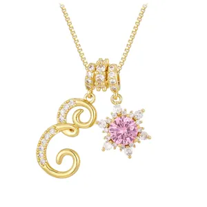 Detail of gold box chain necklace with letter E and pink zircon snowflake charms