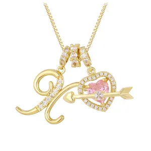Macro detail of gold letter K and pink heart zircon pendant with Cupid's arrow on box chain
