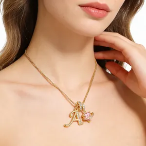Collar dorado con colgante letra A y gema de corazón rosa usado por modelo