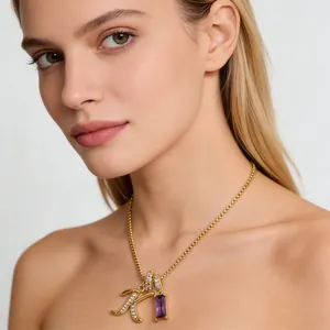 Collana dorata con ciondolo lettera K e zircone viola indossata da modella