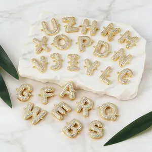Makroaufnahme von 26 Mikro-Pave-Zirkonia-Alphabet-Anhängern auf weißem Marmorgrund