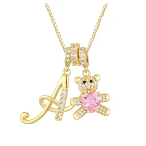 Detailed close-up of golden bear pendant with pink heart stone and letter A necklace