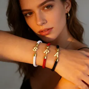 Detailansicht geflochtener Armbänder in Weiß, Rot und Schwarz mit goldenen Buchstaben