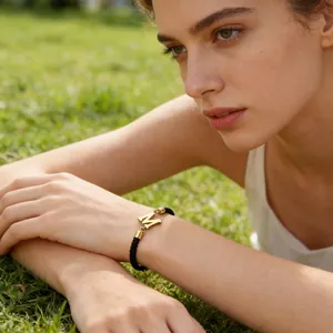 Detailaufnahme eines schwarzen geflochtenen Armbands mit goldenem Buchstaben M Anhänger