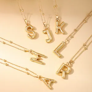 Detalle de colgantes de letras doradas estilo burbuja con cadena de cuentas finas