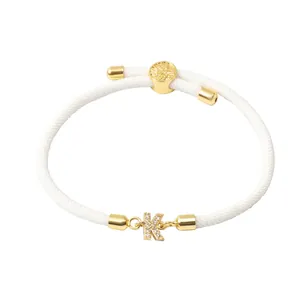 Détail du bracelet en corde tressée blanche avec pendentif lettre K serti de zircons