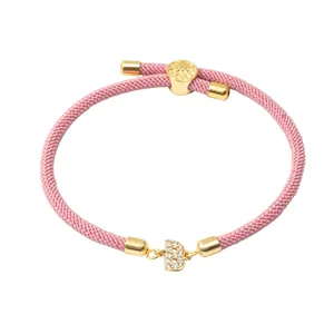 Détail du bracelet tissé rose avec pendentif lettre B en or et micro-pavage en zircone