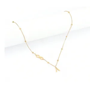 Detail of gold infinity symbol and letter A pendant on a dainty beaded chain necklace