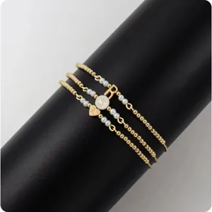 Detaillierte Ansicht von drei goldenen Perlenarmbändern mit Initialen und Perlen