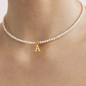 Detail einer eleganten Perlenkette mit goldenem Buchstaben A Anhänger am Hals getragen