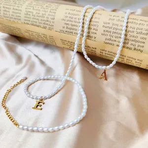 Detail einer Vintage-Perlenkette mit goldenen Buchstabenanhängern und Verlängerung