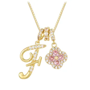 Golden clover necklace with pink zircon and micro-pave letter F pendant on white background