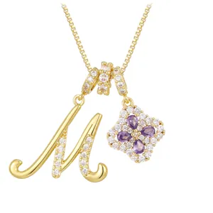 Collier doré avec pendentif lettre M et trèfle en pierre violette sur fond blanc pur