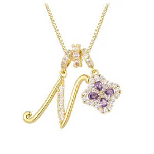 Collier lettre N dorée avec pendentif trèfle en zircon violet sur fond blanc pur