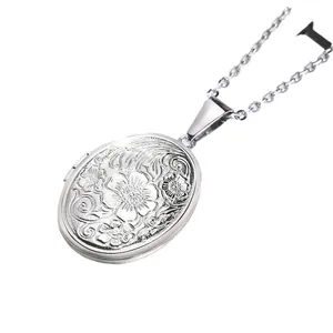 Vintage silver oval locket necklace with intricate floral relief carving on white background