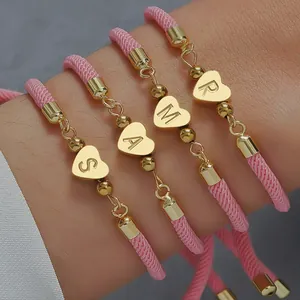 Detailansicht von 4 verstellbaren rosa Flechtarmbändern mit goldenen Herzanhängern